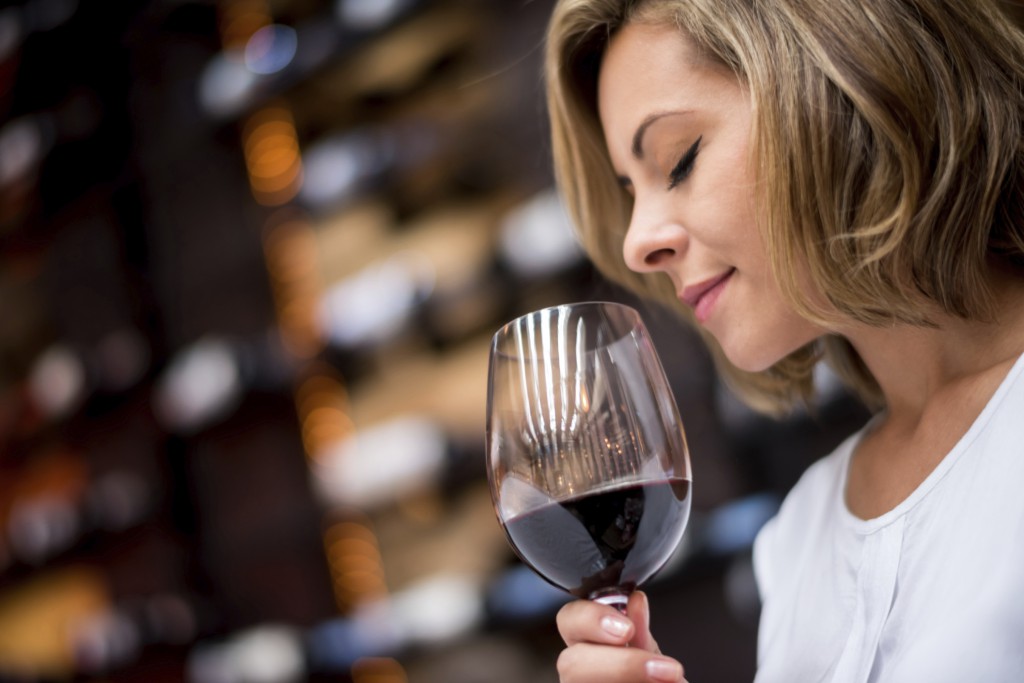 Woman tasting wine at a cellar smelling into a glass