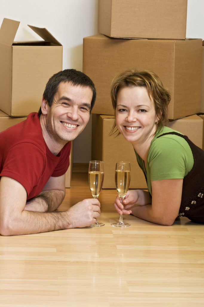 Couple toasting in their new home among cardboard boxes