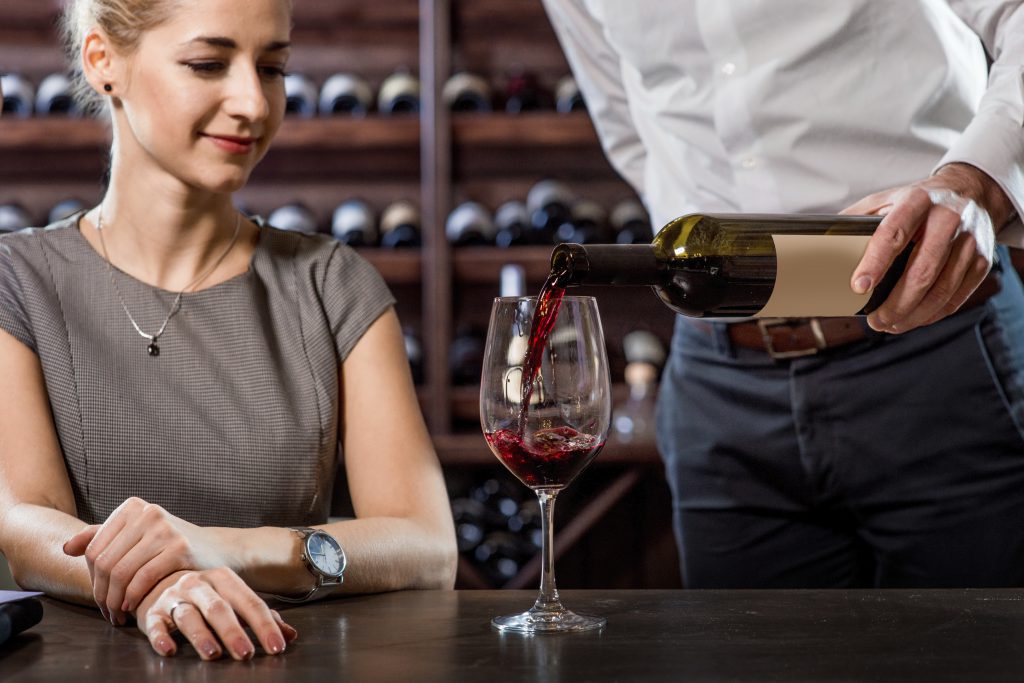 Sommelier pouring wine to the glass with woman in the cellar. Wine degustation